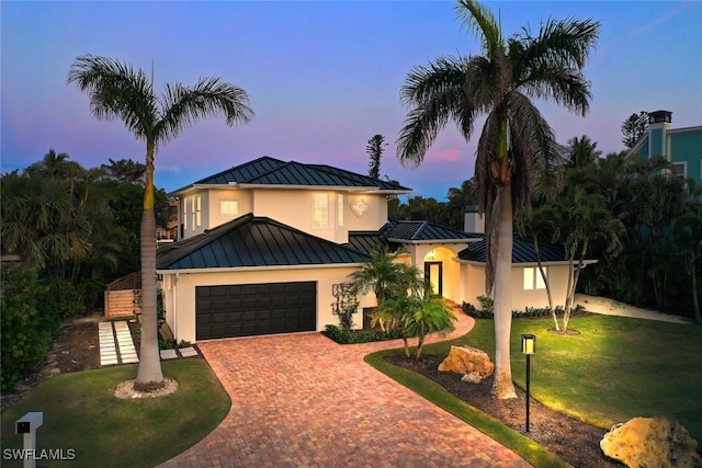 view of front of home with a garage, metal roof, a standing seam roof, decorative driveway, and a yard