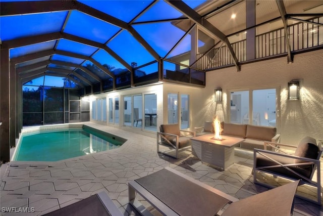 outdoor pool featuring glass enclosure, a patio, and an outdoor living space with a fire pit