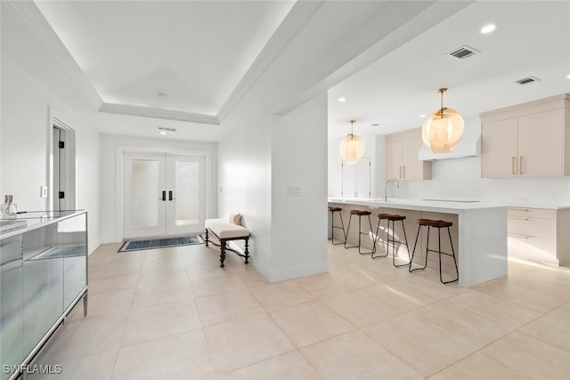 interior space with light tile patterned floors, visible vents, a tray ceiling, french doors, and recessed lighting