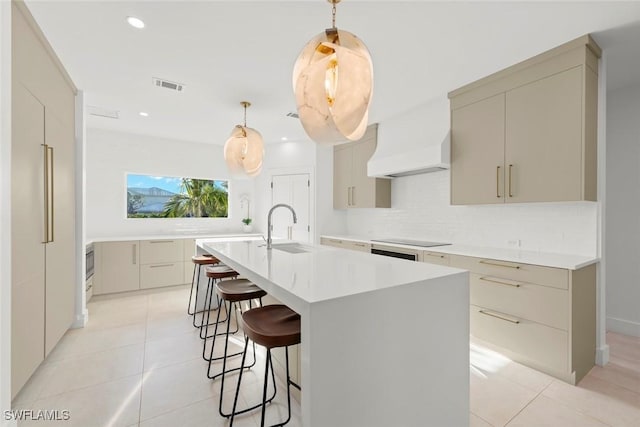 kitchen featuring light tile patterned floors, black electric cooktop, a sink, custom exhaust hood, and decorative backsplash