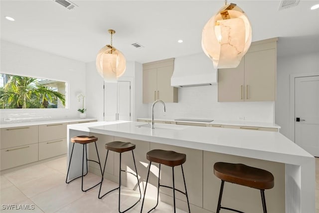 kitchen featuring a sink, visible vents, light countertops, tasteful backsplash, and custom range hood