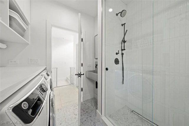 bathroom featuring tile patterned floors, washer and dryer, a shower stall, and baseboards