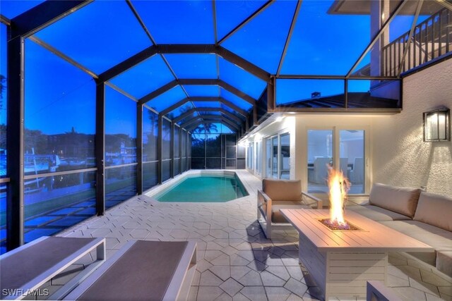 outdoor pool featuring an outdoor living space with a fire pit, a patio, and a lanai