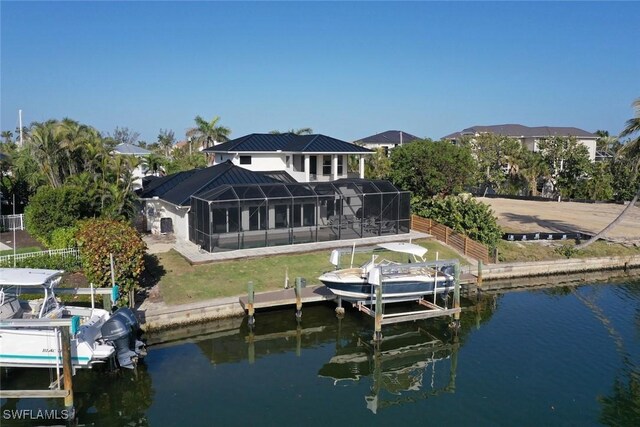 back of property with a water view, glass enclosure, boat lift, and fence