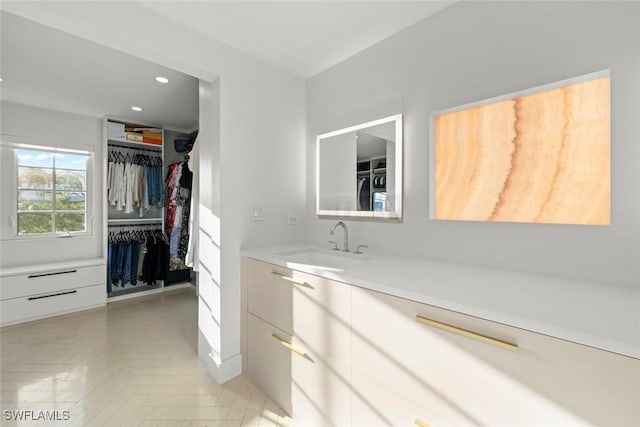 bathroom with a spacious closet, vanity, and recessed lighting