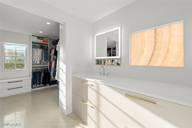 bathroom featuring a walk in closet, vanity, and recessed lighting