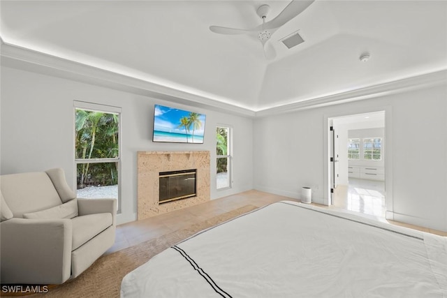 bedroom featuring visible vents, a raised ceiling, lofted ceiling, ceiling fan, and a high end fireplace