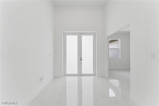 empty room featuring marble finish floor, french doors, and baseboards