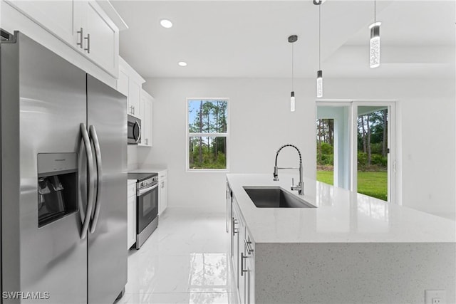 kitchen with a center island with sink, appliances with stainless steel finishes, marble finish floor, white cabinetry, and a sink