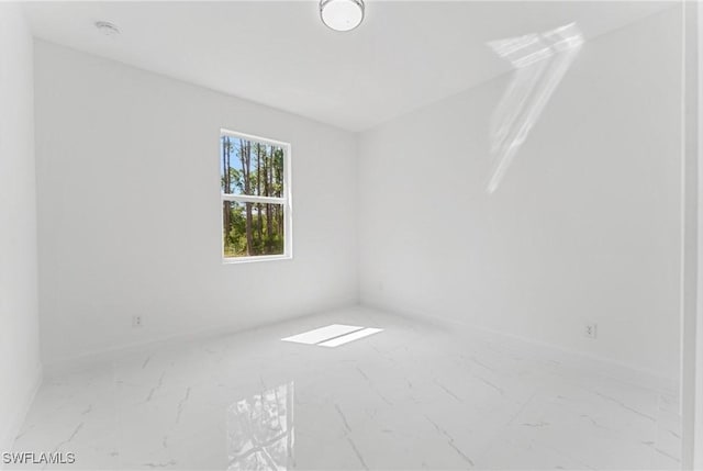 spare room with marble finish floor and baseboards