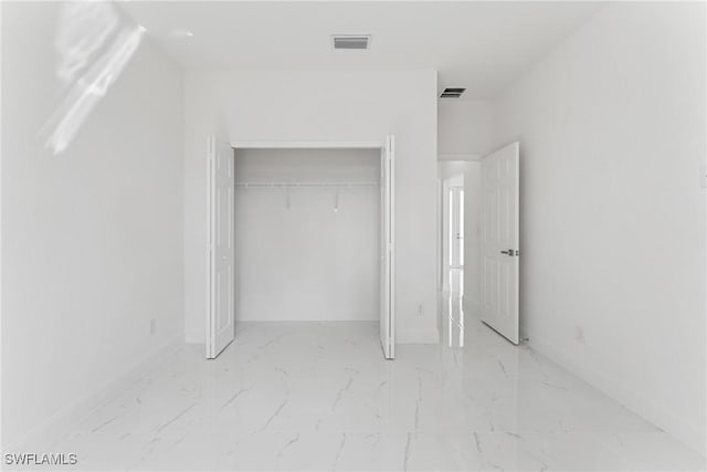 unfurnished bedroom with marble finish floor, visible vents, and a closet