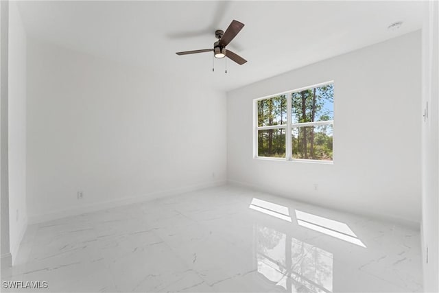 spare room featuring marble finish floor, ceiling fan, and baseboards