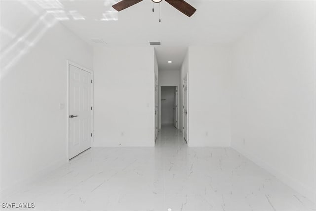 unfurnished room with a ceiling fan, marble finish floor, visible vents, and baseboards