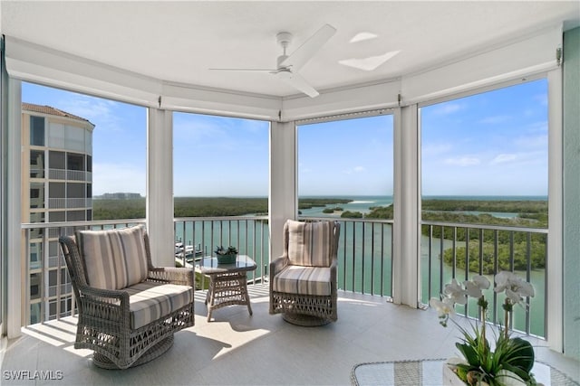 sunroom with a ceiling fan and a water view