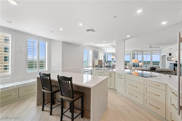 kitchen with visible vents, a sink, open floor plan, a center island, and black electric stovetop