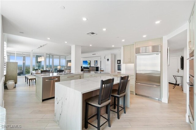 kitchen with a spacious island, visible vents, light wood-style floors, stainless steel appliances, and a sink