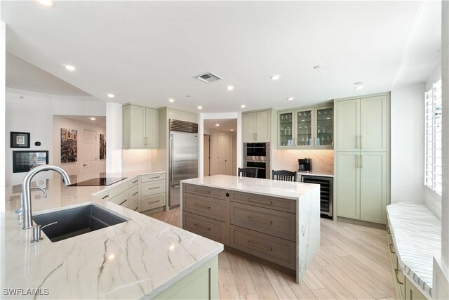 kitchen with light stone counters, visible vents, a sink, wine cooler, and appliances with stainless steel finishes