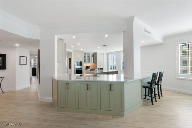 kitchen featuring visible vents, green cabinetry, a peninsula, white cabinetry, and crown molding