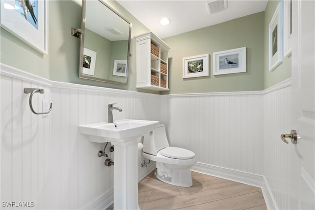 bathroom featuring visible vents, wainscoting, toilet, and wood finished floors