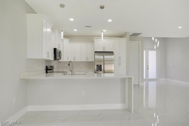 kitchen featuring marble finish floor, light countertops, appliances with stainless steel finishes, a sink, and a peninsula