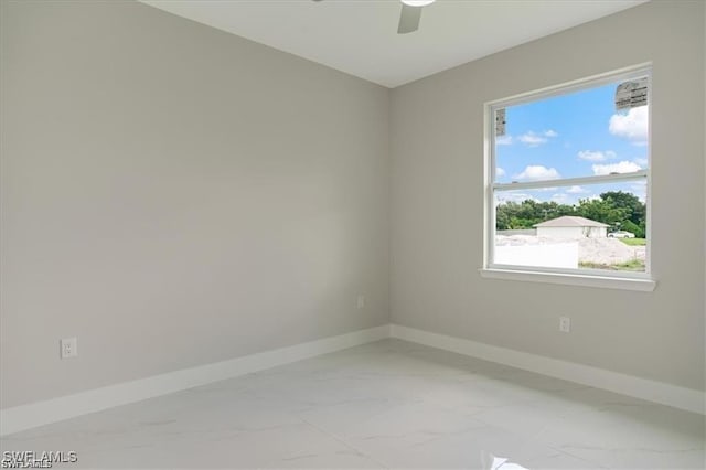 spare room featuring marble finish floor, ceiling fan, and baseboards