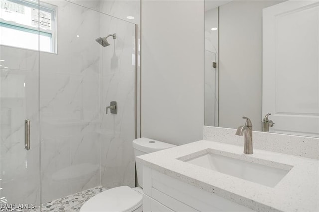 bathroom with a marble finish shower, vanity, and toilet