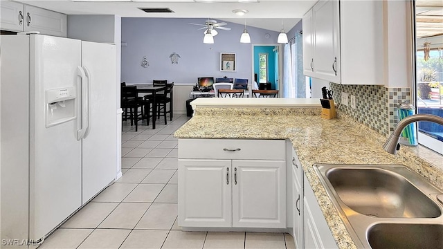 kitchen featuring visible vents, light tile patterned floors, a peninsula, white refrigerator with ice dispenser, and a sink