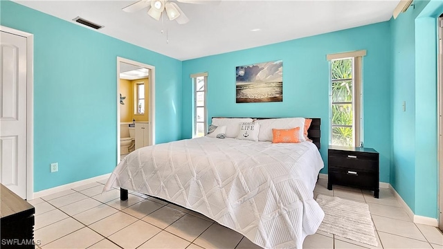 bedroom with visible vents, ensuite bath, light tile patterned floors, baseboards, and ceiling fan