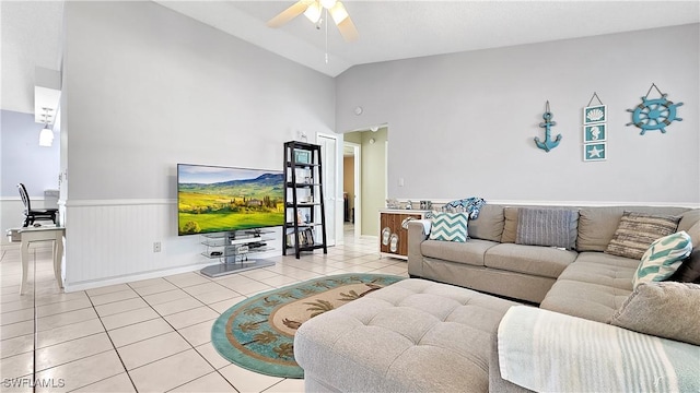 living area featuring vaulted ceiling, light tile patterned floors, a ceiling fan, and wainscoting