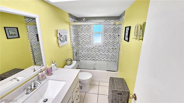 bathroom with tile patterned floors, combined bath / shower with glass door, toilet, and vanity