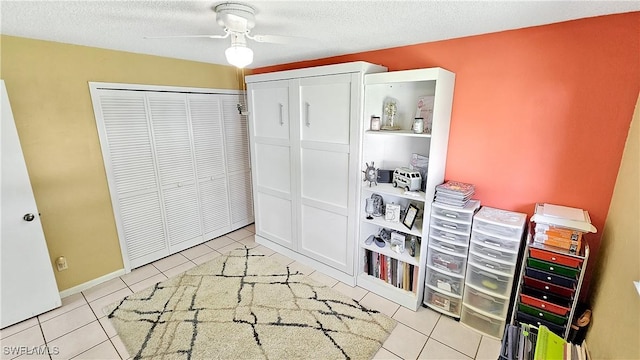 bedroom featuring tile patterned floors, a textured ceiling, a closet, and a ceiling fan