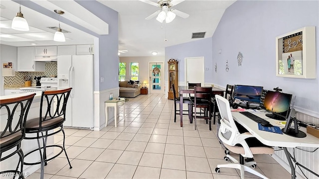 interior space with light tile patterned floors, a ceiling fan, visible vents, vaulted ceiling, and wainscoting