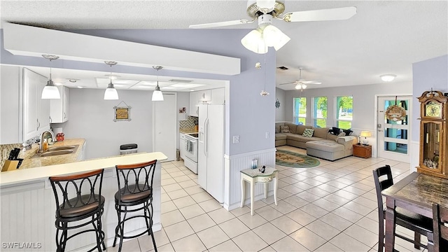 kitchen with light tile patterned floors, a sink, vaulted ceiling, light countertops, and white cabinetry