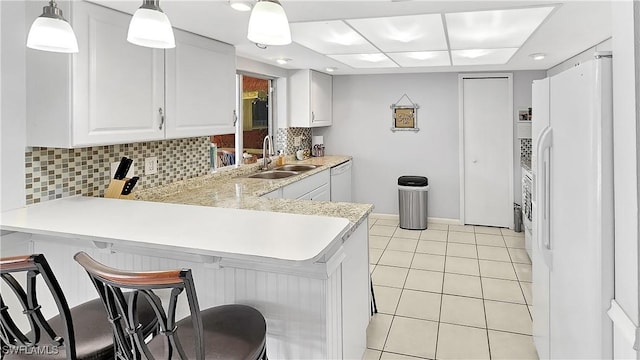 kitchen with white appliances, light tile patterned floors, a peninsula, and a sink