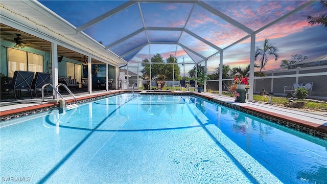 pool at dusk with a patio, a ceiling fan, an outdoor pool, and a lanai