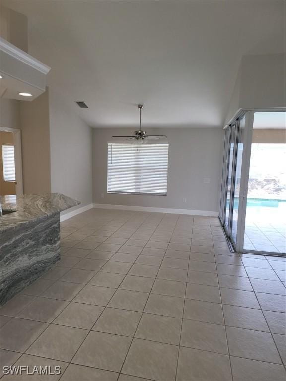 spare room with a ceiling fan, light tile patterned flooring, visible vents, and baseboards