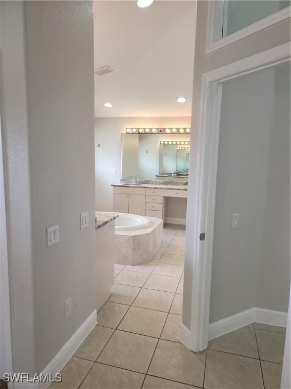 full bathroom featuring tiled bath, vanity, baseboards, visible vents, and tile patterned floors