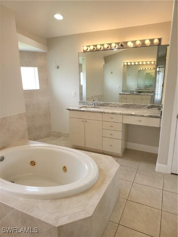 bathroom featuring baseboards, vanity, a tub with jets, and tile patterned floors