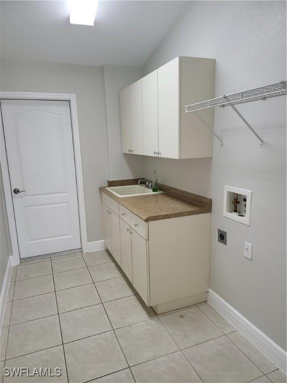 laundry room with light tile patterned floors, washer hookup, a sink, cabinet space, and electric dryer hookup