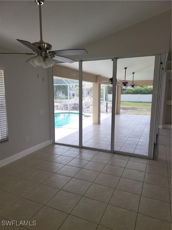 unfurnished room featuring vaulted ceiling, ceiling fan, tile patterned flooring, and baseboards