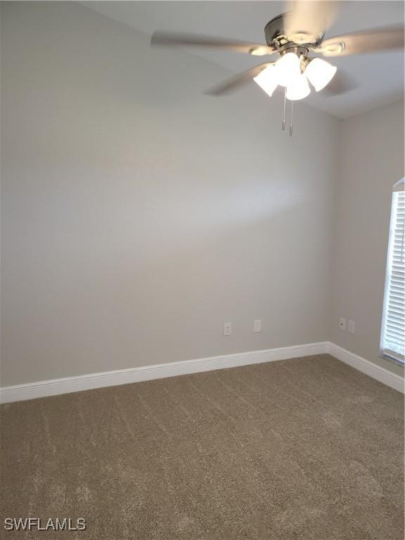 carpeted empty room featuring ceiling fan and baseboards