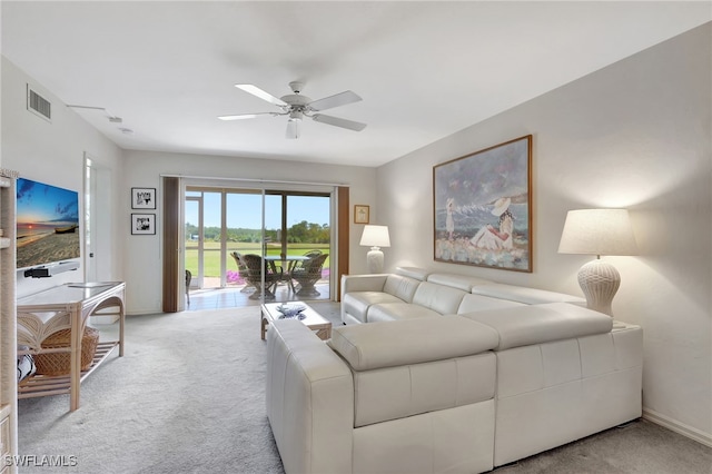 living room featuring ceiling fan, visible vents, baseboards, and light colored carpet