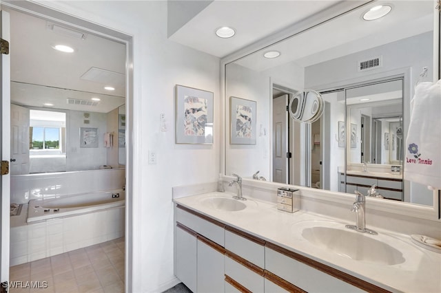 bathroom with a garden tub, a sink, and visible vents