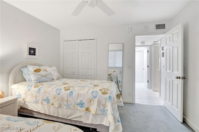 bedroom with tile patterned flooring, carpet floors, visible vents, a ceiling fan, and a closet