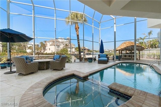 view of pool featuring a lanai, a patio area, a pool with connected hot tub, and a fire pit