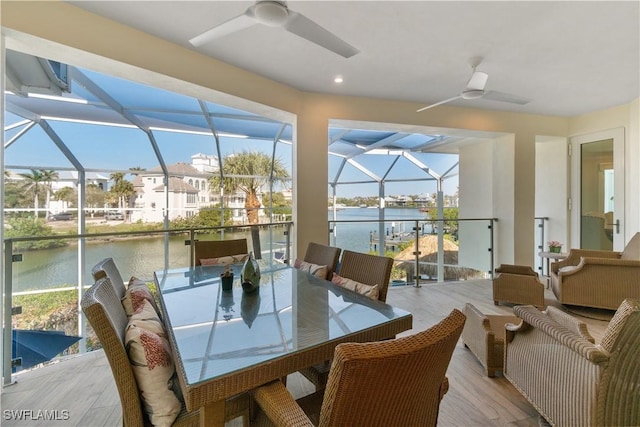 sunroom / solarium with a ceiling fan and a water view