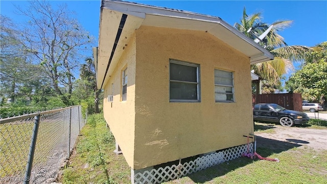 view of side of home with crawl space, fence, and stucco siding