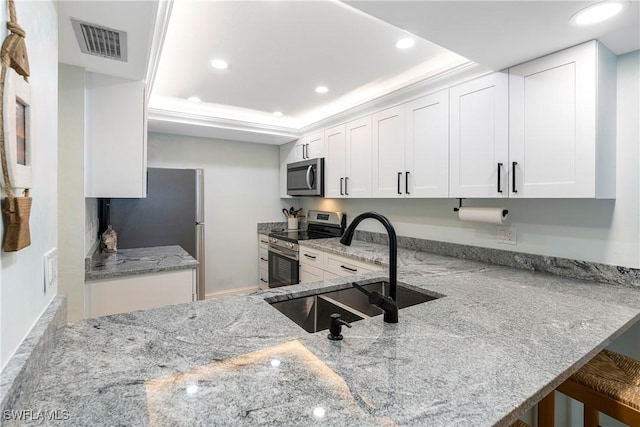 kitchen with stainless steel appliances, visible vents, white cabinets, a sink, and light stone countertops