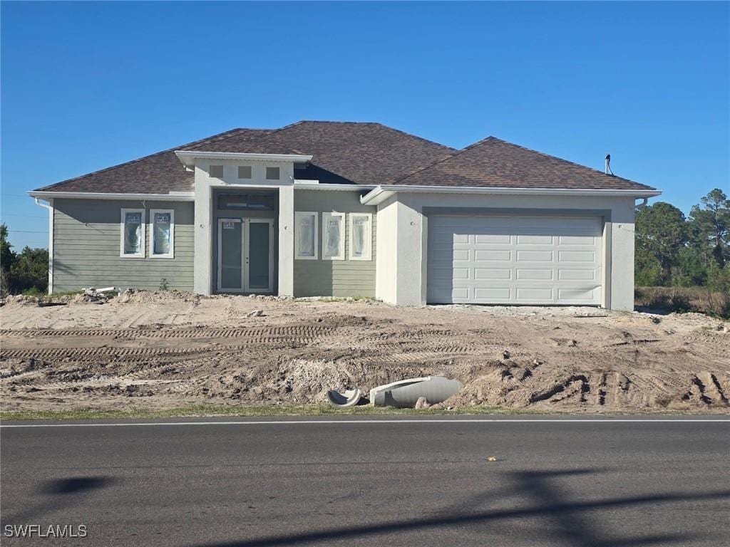 prairie-style home with a garage and dirt driveway