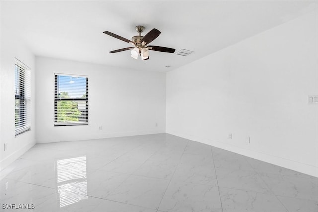 spare room with baseboards, visible vents, and a ceiling fan